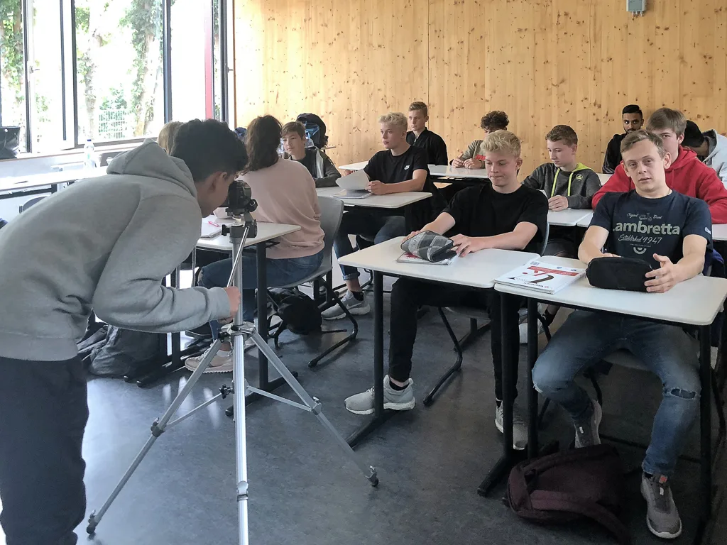 Jugendliche arbeiten mit Kamerastativ im Klassenraum.